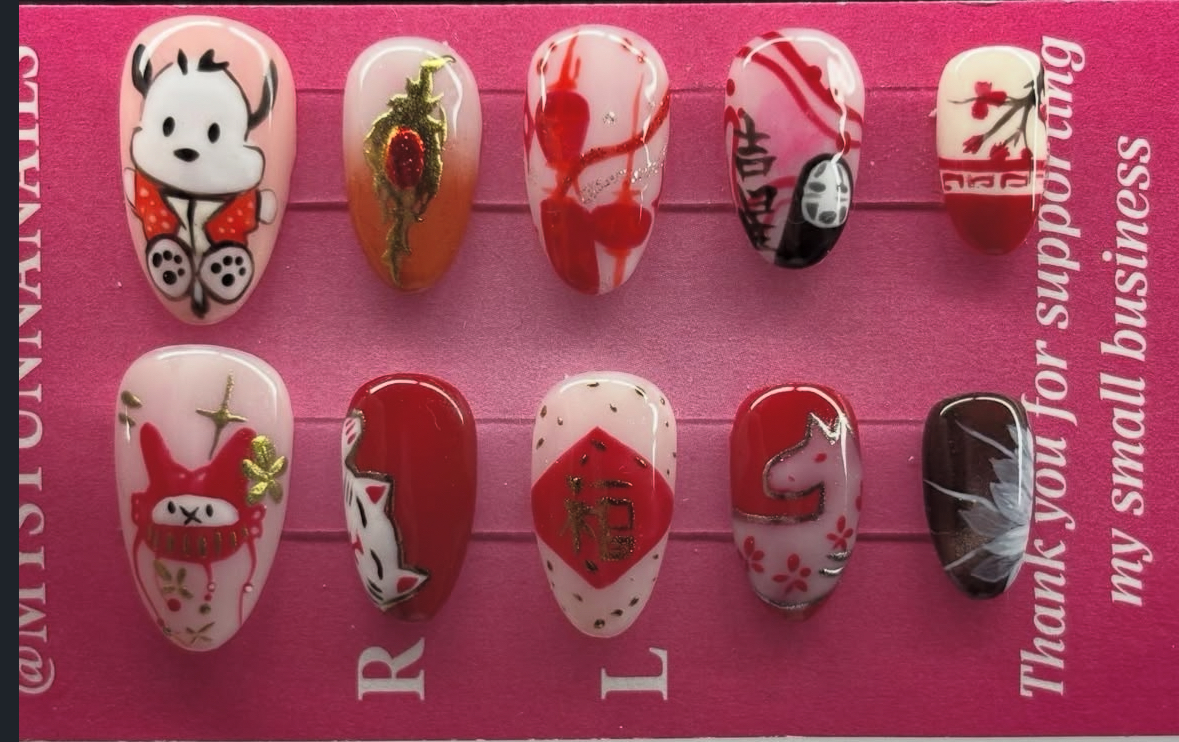 Handmade press-on nail set on a pink display card with red and gold character nail art by mystunnanails